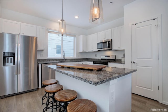 kitchen featuring stainless steel appliances, light wood-type flooring, a sink, and a kitchen breakfast bar