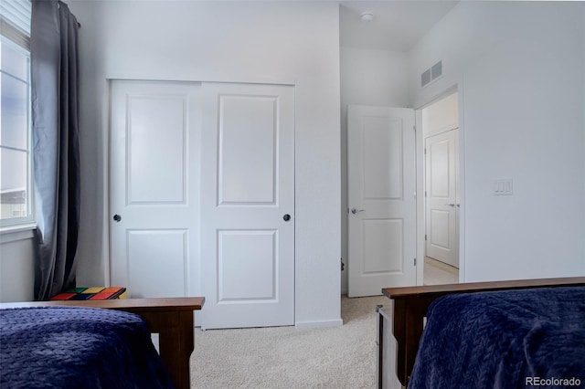 carpeted bedroom featuring a closet, visible vents, and baseboards