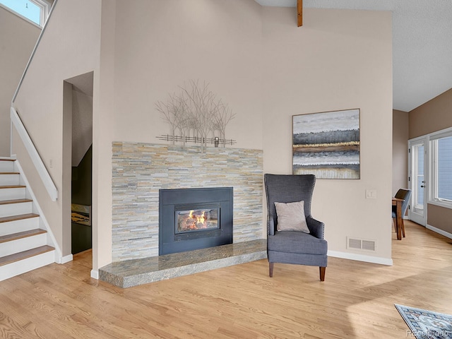 unfurnished room with baseboards, visible vents, a glass covered fireplace, stairway, and wood finished floors