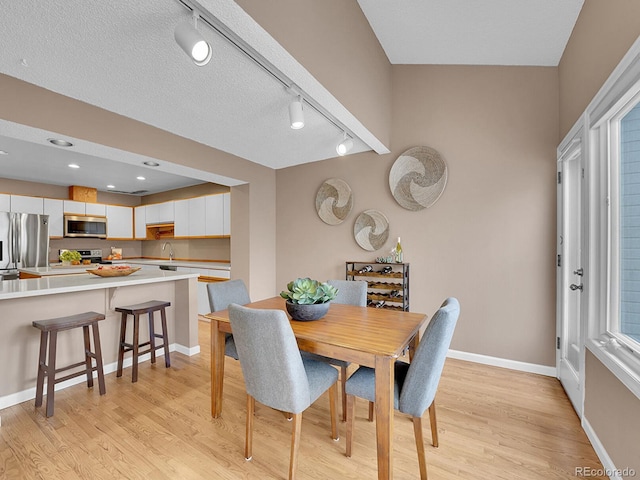 dining area featuring light wood-style floors, baseboards, a textured ceiling, and recessed lighting