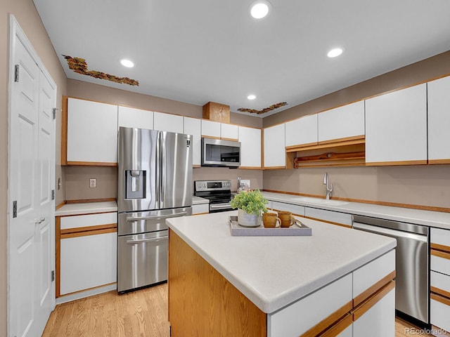 kitchen featuring stainless steel appliances, light wood-type flooring, white cabinetry, a sink, and recessed lighting