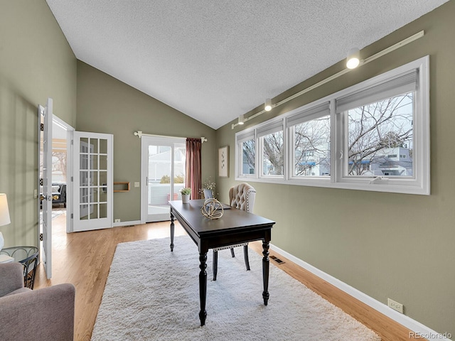 office featuring lofted ceiling, wood finished floors, and baseboards