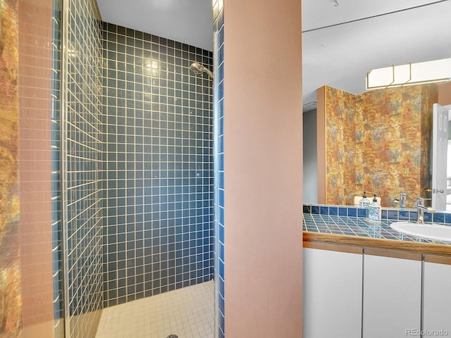 bathroom with a tile shower and vanity