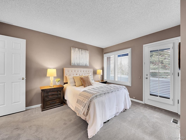 carpeted bedroom with access to exterior, visible vents, a textured ceiling, and baseboards