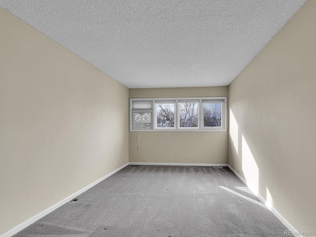 carpeted spare room featuring a textured ceiling and baseboards