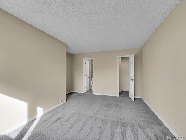 empty room featuring carpet, baseboards, and a textured ceiling