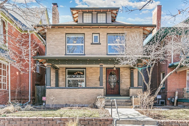 american foursquare style home featuring covered porch, brick siding, and a chimney