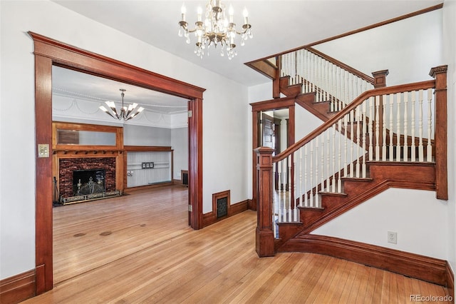 staircase with baseboards, hardwood / wood-style floors, a fireplace, and a notable chandelier