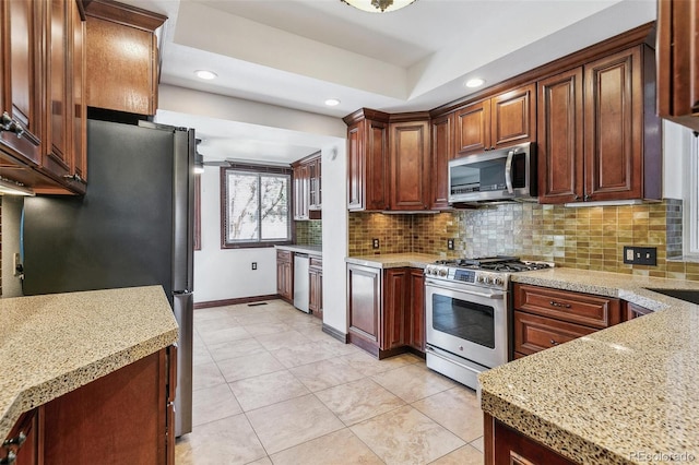 kitchen with light tile patterned floors, tasteful backsplash, a tray ceiling, stainless steel appliances, and recessed lighting