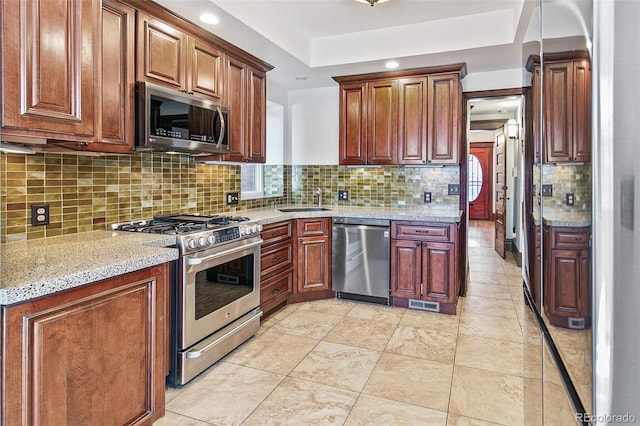 kitchen featuring visible vents, decorative backsplash, a raised ceiling, stainless steel appliances, and a sink