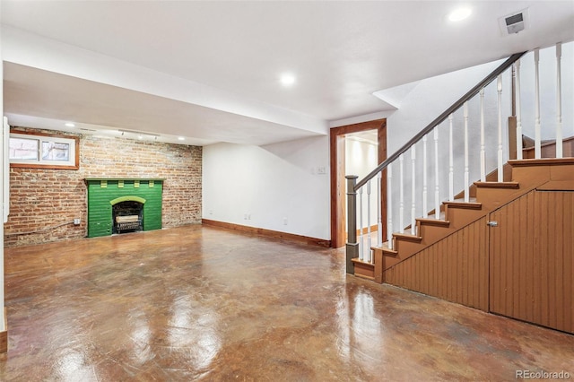 unfurnished living room with brick wall, visible vents, baseboards, finished concrete flooring, and a brick fireplace