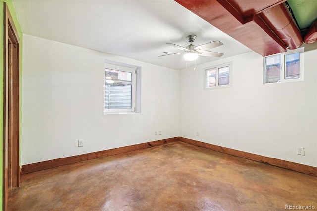 spare room with a ceiling fan, concrete floors, and baseboards