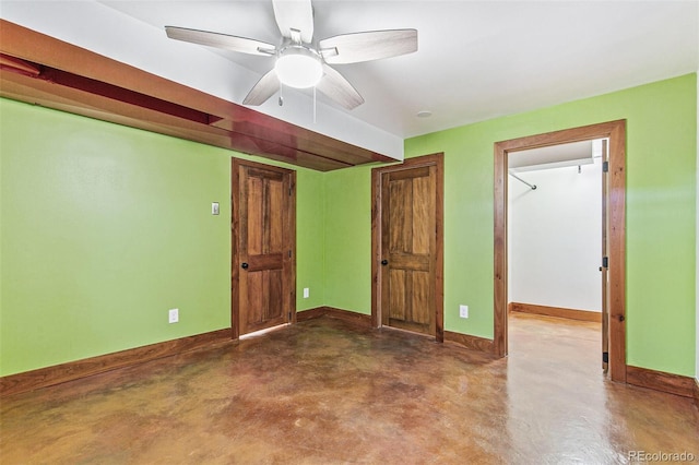 unfurnished room featuring finished concrete flooring, a ceiling fan, and baseboards