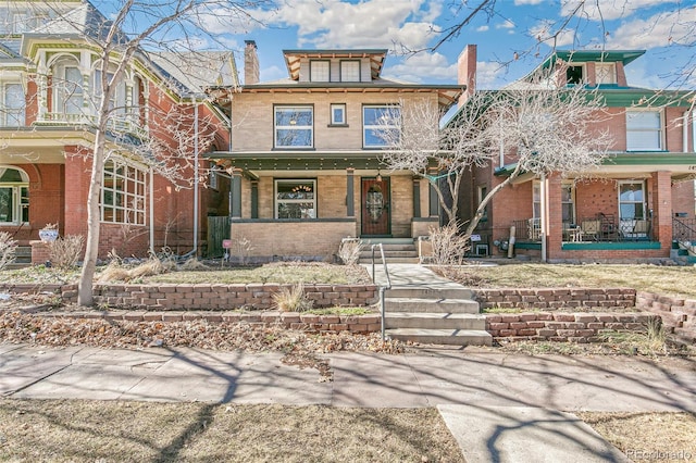 american foursquare style home with covered porch and brick siding