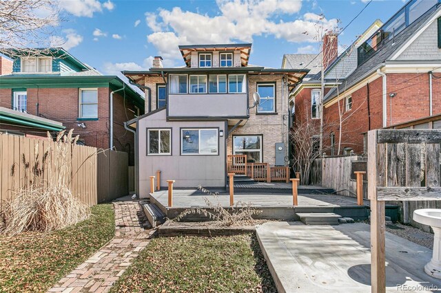 back of property with a deck, a patio area, and fence