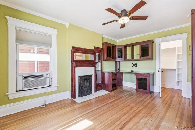 unfurnished living room with light wood finished floors, a fireplace with flush hearth, ceiling fan, crown molding, and cooling unit