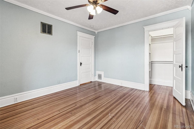 unfurnished bedroom featuring visible vents, crown molding, baseboards, and hardwood / wood-style flooring