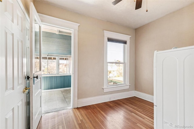 interior space with washer / dryer, a ceiling fan, baseboards, and wood finished floors