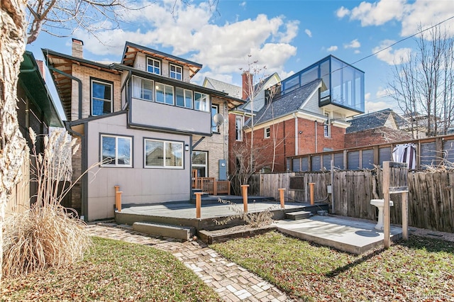 rear view of property with a deck, a chimney, and fence