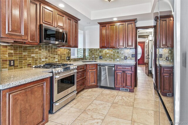 kitchen featuring visible vents, tasteful backsplash, light stone counters, a sink, and appliances with stainless steel finishes