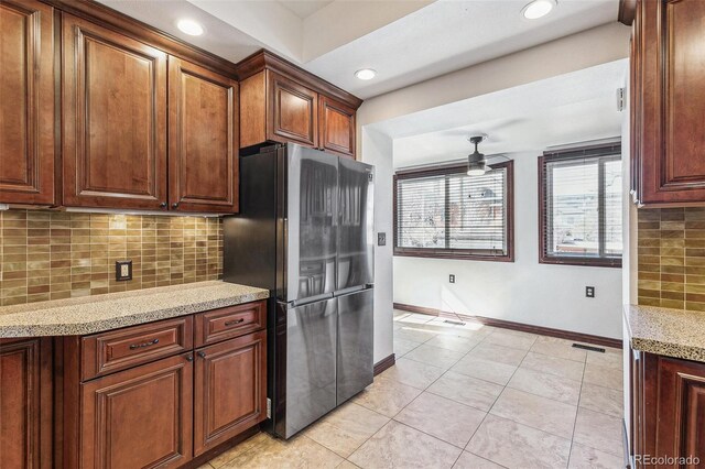 kitchen with freestanding refrigerator, light tile patterned flooring, baseboards, a ceiling fan, and backsplash