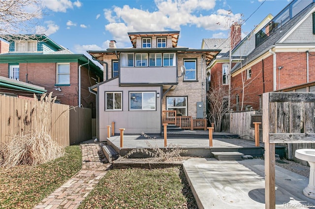 rear view of property featuring a deck, fence, and a patio