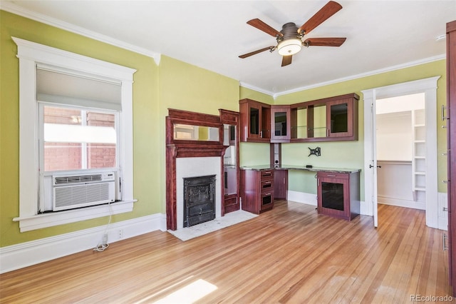 unfurnished living room with ceiling fan, a fireplace with flush hearth, crown molding, cooling unit, and light wood-style flooring