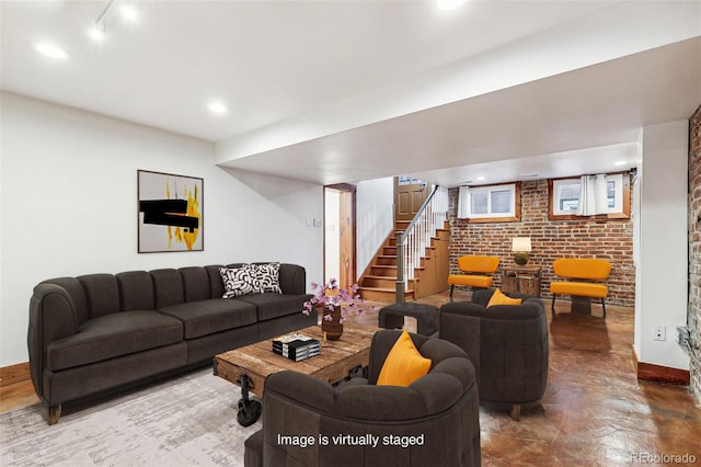 living room featuring brick wall, baseboards, stairway, recessed lighting, and concrete floors