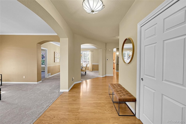 entrance foyer featuring a textured ceiling, light wood-type flooring, and crown molding