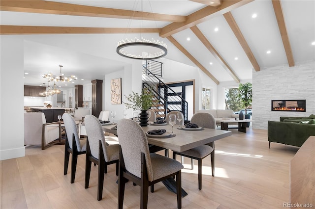 dining room with high vaulted ceiling, a fireplace, beamed ceiling, light hardwood / wood-style floors, and a chandelier