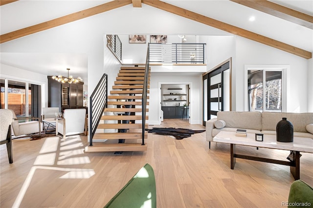 interior space with beam ceiling, light hardwood / wood-style flooring, high vaulted ceiling, and an inviting chandelier