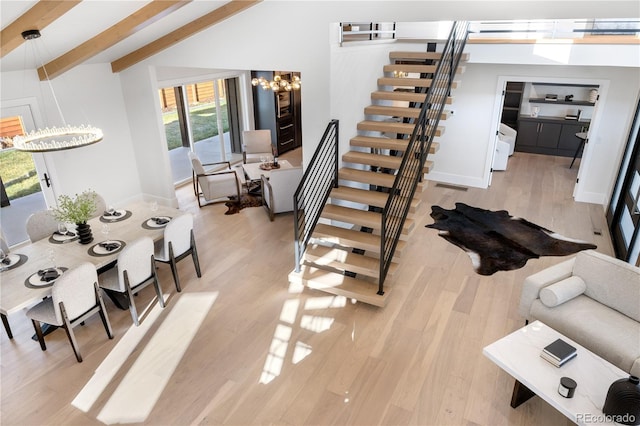 staircase with vaulted ceiling with skylight, hardwood / wood-style floors, and an inviting chandelier