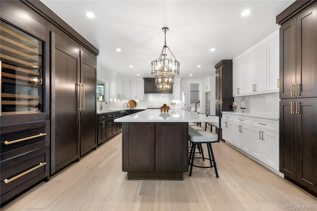 kitchen featuring backsplash, white cabinets, a kitchen island, hanging light fixtures, and a breakfast bar area