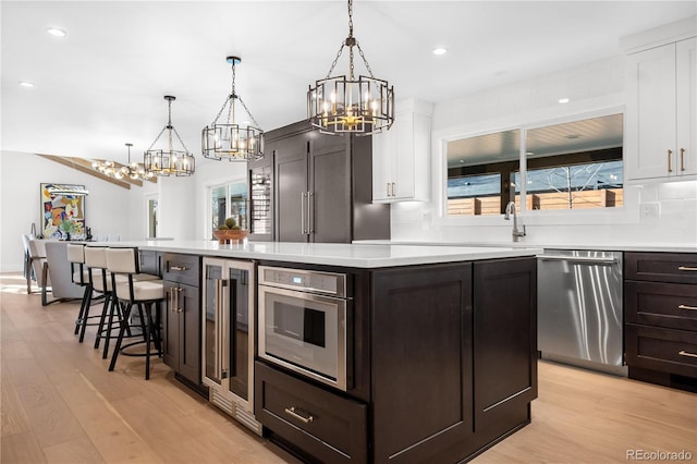 kitchen with white cabinets, a center island, decorative light fixtures, and stainless steel dishwasher