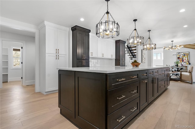 kitchen featuring white cabinetry, a kitchen island, hanging light fixtures, and light hardwood / wood-style floors