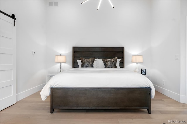 bedroom with a barn door and light wood-type flooring