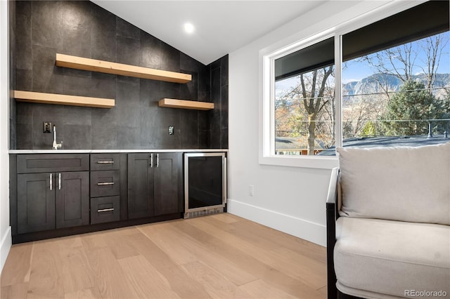 bar with light hardwood / wood-style flooring, beverage cooler, lofted ceiling, and sink