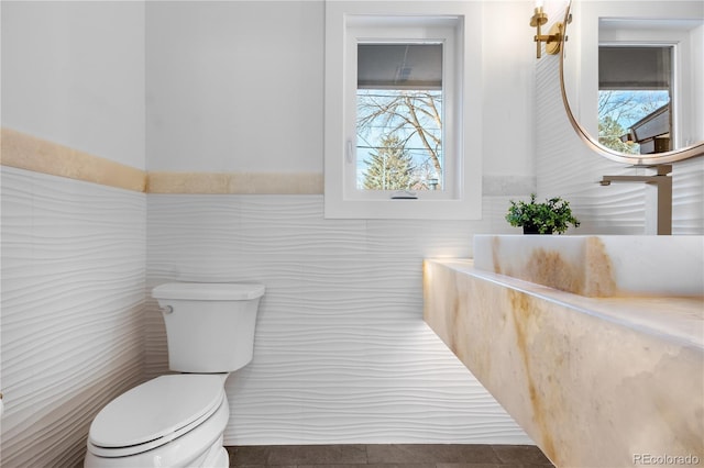 bathroom with toilet and tile walls