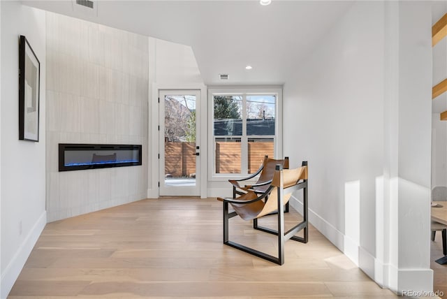 sitting room featuring a tile fireplace and light wood-type flooring