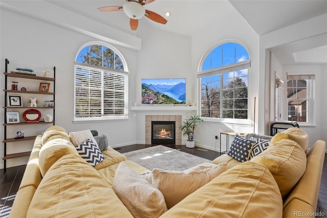 living room with dark wood-type flooring, ceiling fan, lofted ceiling, and a fireplace