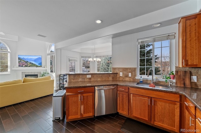 kitchen featuring dark stone countertops, stainless steel dishwasher, pendant lighting, and sink