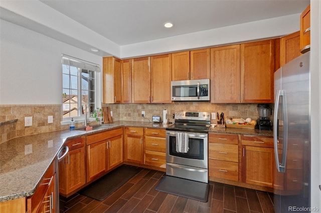 kitchen featuring sink, backsplash, stone counters, and stainless steel appliances