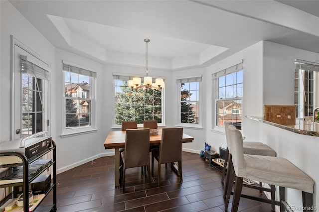 dining space with a wealth of natural light, a tray ceiling, and a notable chandelier