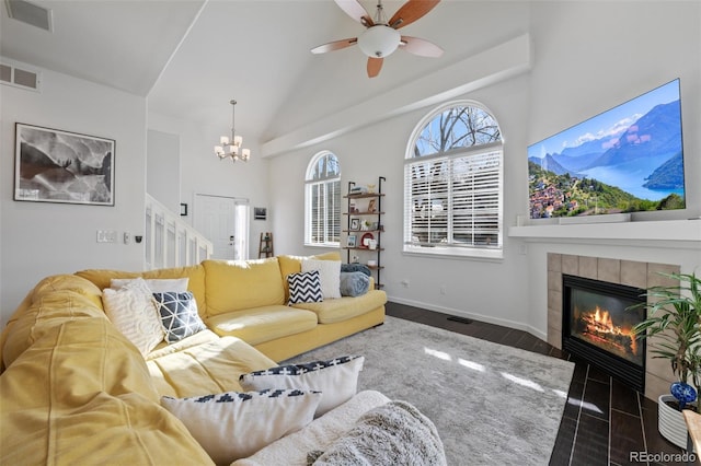 living room with ceiling fan with notable chandelier, dark wood-type flooring, and a tiled fireplace