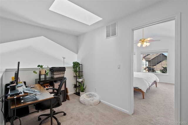 carpeted office with ceiling fan and lofted ceiling with skylight