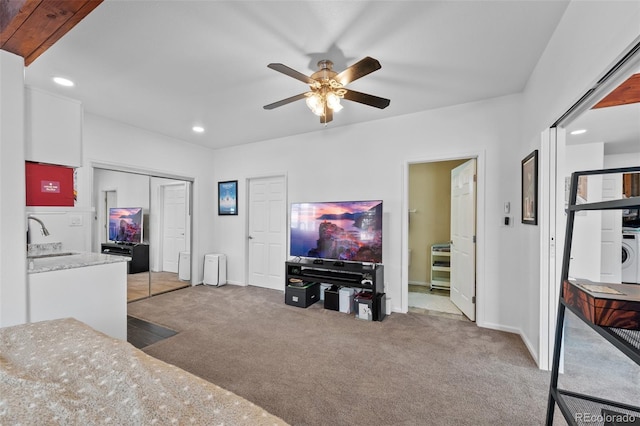 living room featuring washer / dryer, ceiling fan, light colored carpet, and sink