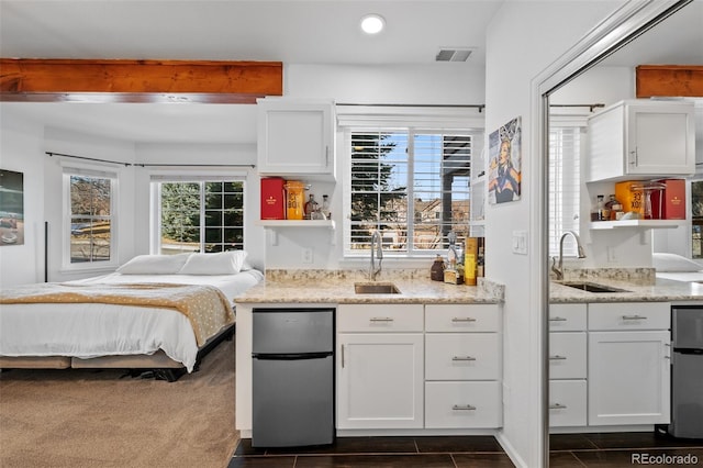 kitchen featuring stainless steel fridge, sink, and white cabinetry