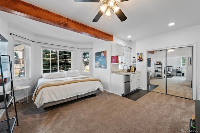 bedroom with ceiling fan, beam ceiling, a closet, and dark colored carpet