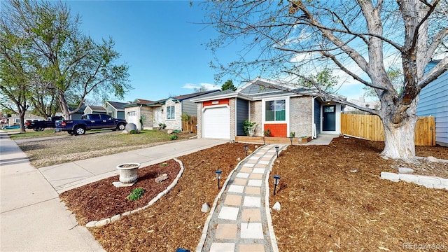 view of front of home with brick siding, fence, driveway, and a garage