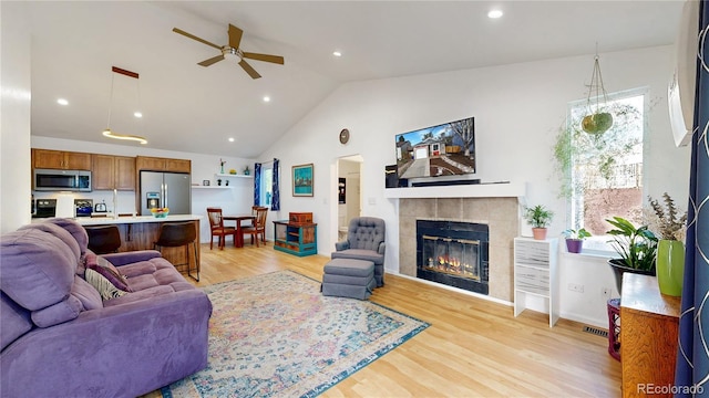 living room with a ceiling fan, visible vents, a tiled fireplace, light wood-style floors, and recessed lighting